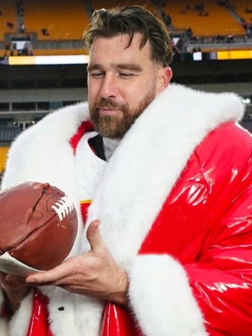Person in a Santa Claus outfit holding a football in an indoor sports arena.