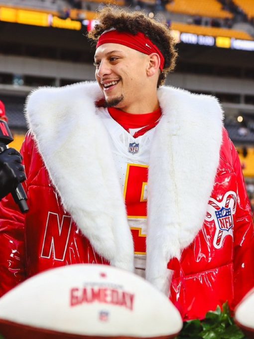 Person wearing a red sports jacket with white fur trim, holding a football, in an indoor sports arena setting.