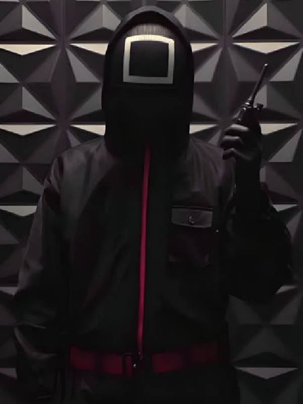 Person wearing a dark jacket with a geometric patterned wall in the background